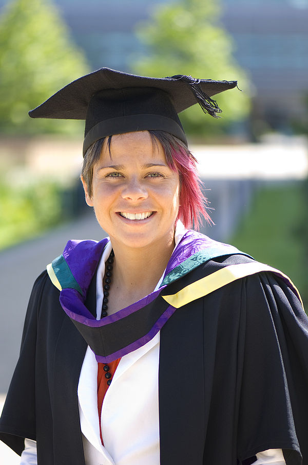 Edge Hill University's academic colors of heliotrope (purple), gold, and green seen on the hood of honorary graduate Sue Smith