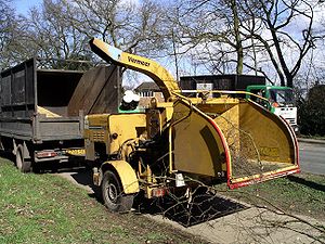 A portable woodchipper and truck with wood chips collected in the truck bed.
