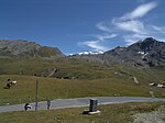 Gränssten mellan Schweiz och Italien vid vägskylten som markerar passets krön. Åt höger Italien, åt vänster Schweiz. I fjärran syns hotellen vid Stelviopasset.