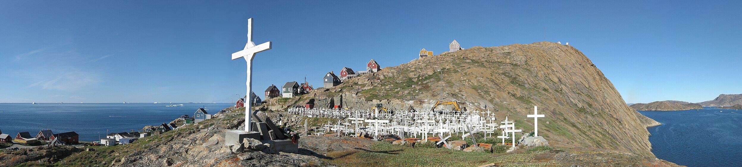 Panorama over Upernavik cemetery from the southern end of the island in North-West Greenland. At the time, the cemetery was in the process of being expanded, as it was running out of space. Thus, the construction work in the background. Individual photos taken with a Canon IXUS 800IS. Cylindrical projection. Foreground patched with frames taken two weeks later.