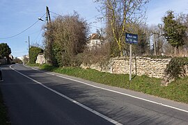 Vue d'une route en pente à l’entrée d'un groupe de maisons ; bâtiments sur la droite.