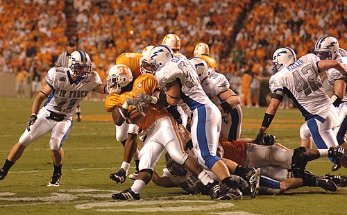 Air Force Academy Falcons free safety Bobby Giannini (#11) prepares to finish off Tennessee tailback Montario Hardesty, while Falcons defensive end Josh Clayton (#97) loosens Hardesty's grip on the football. The Falcons lost 31–30 in 2006.