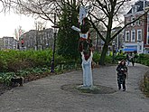 Amsterdam city, people are walking near a wooden tree sculpture at the square Frederiksplein; photo by Fons Heijnsbroek, January 2022