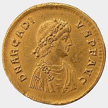 Awers monety przedstawiający profil popiersia mężczyzny w todze i głowę otoczoną wawrzynami.