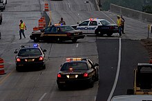 Four persons running and about four police cars from various services