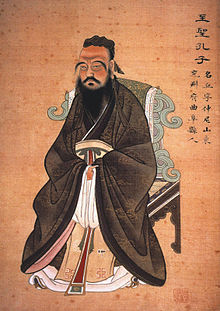 Dessin d'un homme assis avec une longue barbe noire et les bras dans ses manches.