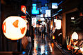 Narrow streets of historical part of Kyoto decorated with all kinds of traditional japanese lanterns at a rainy city night