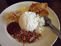 Malaysian nasi lemak, is served with anchovies, peanuts, boiled egg, lamb curry, cucumber, and sambal.