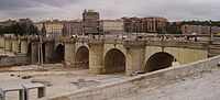 El puente de Toledo, en junio de 2007, cuando se encontraba protegido por una lona para evitar su deterioro durante las obras de soterramiento de la autopista de circunvalación M-30 y la posterior creación, sobre el terreno liberado, de un parque lineal a lo largo de las riberas del río Manzanares.