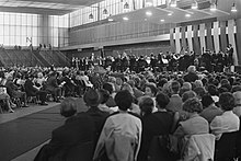 Foto en blanco y negro: una sala de conciertos, la orquesta en el estrado.