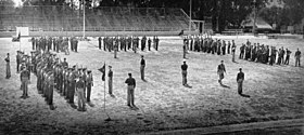 Sotilaat seisovat muodostelmassa ryhmissä amerikkalaisen jalkapallon kentällä