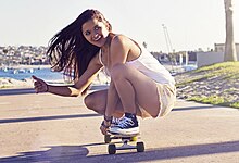 A skateboarder displaying the shaka sign while riding her longboard San Diego girl riding a longboard (mod).jpg