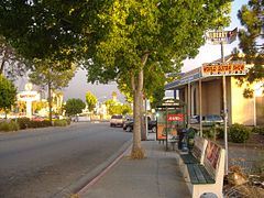 Tree-lined San Pablo Avenue at Macdonald Avenue with an AC Transit BRT stop and businesses in eastern Richmond.