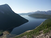 Un calmo specchio d'acqua serpeggia tra ripidi pendii.