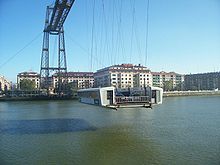 Korb mit einigen Fahrzeugen und Passagieren, der den Fluss überquert