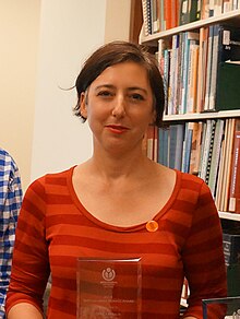 Kapsalis looking toward the camera with a slight smile holding an outstanding service award.