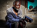 A South Sudanese man listening to radio at his home.jpg