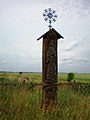 Roofed pillar tipped with an ornate iron cross with floral motif. Angiras village, northwest of Josvainiai.