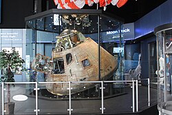 The Apollo 16 capsule, which orbited the Moon 64 times in 1972, is displayed with the recovery parachute hanging above it. Apollo 16 capsule.JPG