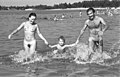 Woman, man and child playing in water (sexual dimorphism, public nudity, water recreation)