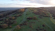 Dolebury Warren 30 minutes after sunrise looking east by northeast showing the northern, eastern, and southern ramparts. Photograph taken January 2024. Dolebury Warren.jpg