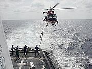 燃料ホースを船から引き上げるアメリカ沿岸警備隊のヘリ