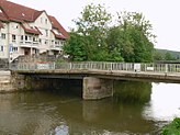 Die inzwischen abgerissene Löwenbrücke mit dem Standort des Brückenlöwen am Ufer im Bereich der Bäume, 2016