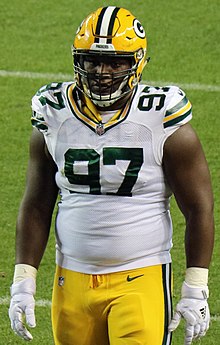 Kenny Clark standing on a field in his uniform