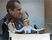 1972 Cumhuriyet Konvansiyonu kürsüsünde Pat Nixon, (iki adam ve arka planda bir poster).