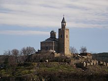 View of a medieval church and bell tower topping a hill surrounded by medieval ruins