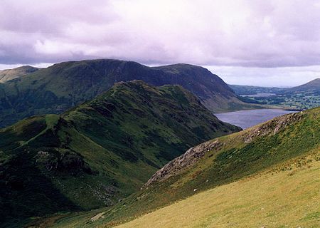 Rannerdale Knotts seen across Rannerdale from the slopes of Whiteless Pike with the fell of Mellbreak in the background. Rannerdale Knotts from Whiteless Breast.jpg