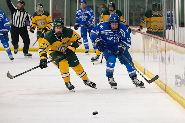 A Seawolves player (left) chases the puck during a 2023 game against Air Force at Avis Alaska Sports Complex
