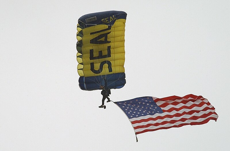 File:US Navy 040507-N-6932B-001 Electrician's Mate 1st Class Eli Ellefson, assigned to the U.S. Navy Parachute Team Leap Frogs, carries the National Ensign.jpg