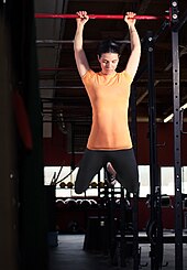 Kipping pull-up Woman in orange doing CrossFit pull-up (February 26 2010).jpg