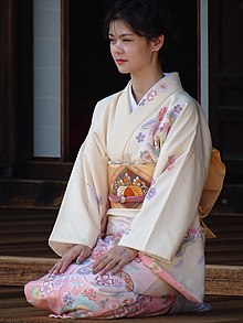 A young woman wearing a light yellow kimono sat kneeling.