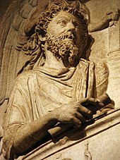 Estatua de un hombre barbudo con cabello rizado en un fresco.