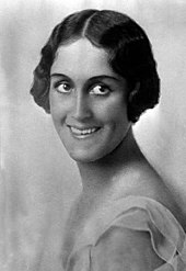 Photographie en noir et blanc d'une jeune femme brune souriante.