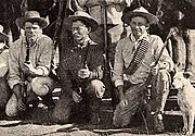 Photo taken in 1893 of three Bulawayo field scouts kneeling in front of their horses. Bob Bain on the left, Burnham in the middle, Maurice Gifford and his dog on the right