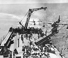 One of Biloxi's SO3Cs landing astern of the ship, while another sits on the port catapult Curtiss SO3C returns to USS Biloxi (CL-80) in 1943.jpg