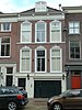 Bedrijfspand met bovenwoning, voorgevel uit de jaren zeventig van de 19de eeuw in rijke eclectisch-classicistische vormen.