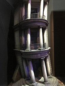 Photo of the model of Gringotts Bank, it is a leaning building with three sets of pillars.