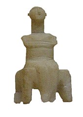 petite statue en marbre : une figure masculine, bras croisés, assis sur un banc