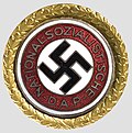 Golden Party Badge of the Nazi Party with a black swastika rotated 45 degrees on a white disc.