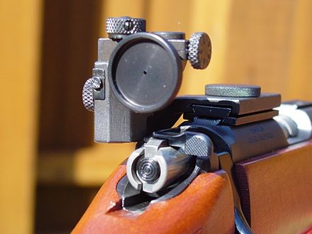 A target aperture sight, mounted on the receiver. This rearward mounting position provides a long sight radius, and the small aperture provides a long depth of field and precise alignment