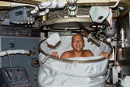 Pete Conrad in the Skylab shower in 1973 behind the Skylab shower enclosure which was made of Beta cloth stretched between rings.
