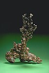 An irregular piece of native copper on a green background.