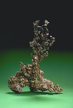 An irregular piece of native copper on a green background.