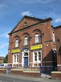 En victoriansk murstensbygning med skilte på forsiden på engelsk og Punjabi.  Frisen lyder "UNITED METHODIST FREE CHURCH 1877", mens skiltet ved døren står "SRI GURU NANAK SIKH TEMPLE".