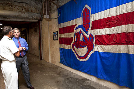 Navy Adm. James A. Winnefeld Jr. (left), vice chairman of the Joint Chiefs of Staff, and Jim Folk (right), vice president of ballpark operations for the Cleveland Indians, discuss the Chief Wahoo battle flag at Progressive Field, 2012