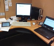 A librarian's workspace at Newmarket Public Library in 2013. iPad, PC, eReader and laptop computer are required tools. Digital services librarian desk.jpg
